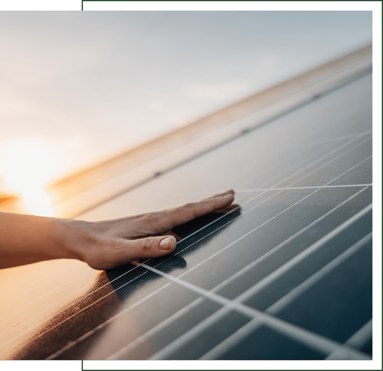 Hand touching solar panel at sunset.