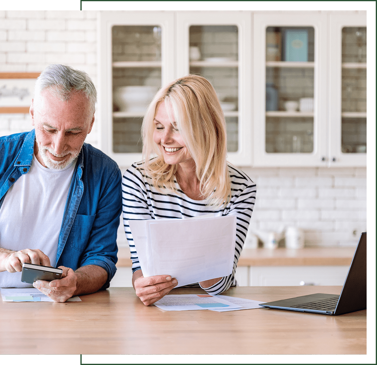 Smiling couple doing finances in kitchen.