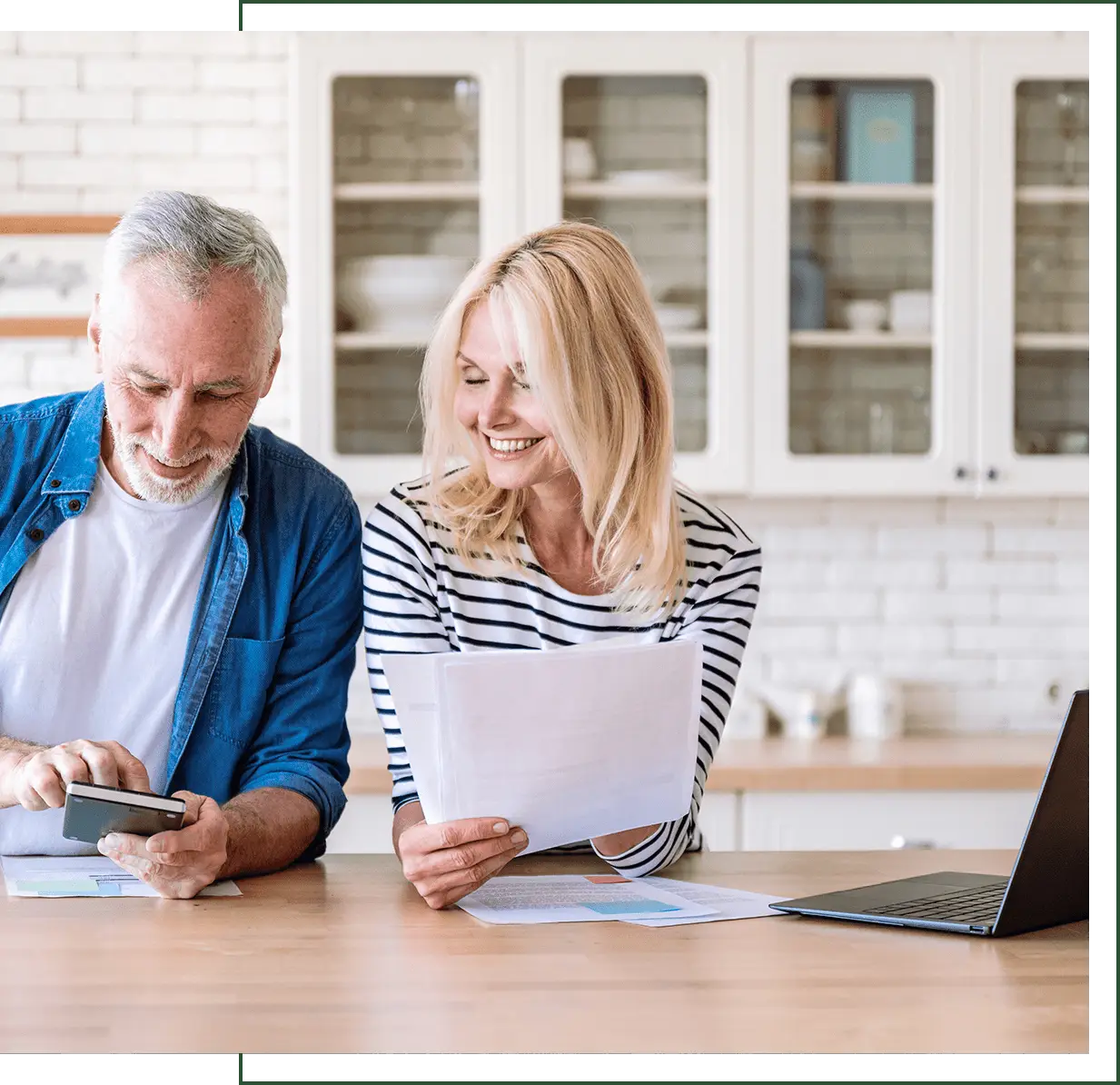 Older couple reviewing documents at kitchen counter.