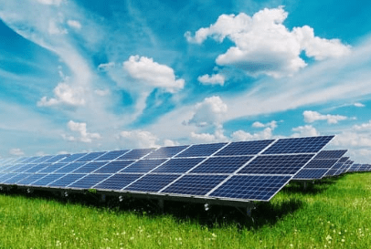 Solar panels in a green field, sunny sky.